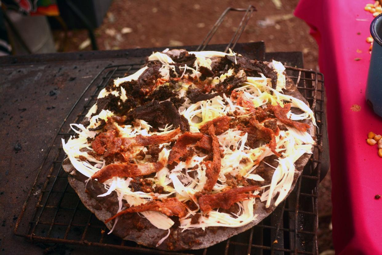 tlayuda being cooked in the stove or anafre in mexico, delicious huge tortilla with beans, oaxaca cheese and jerky beef