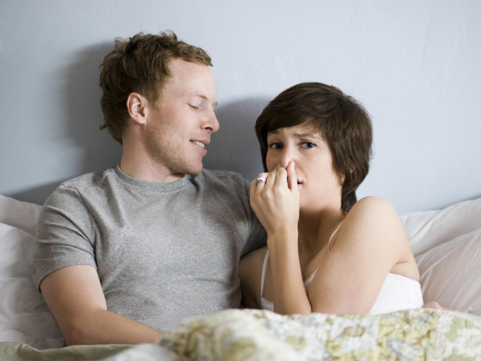 A couple in bed as a woman plugs her nose