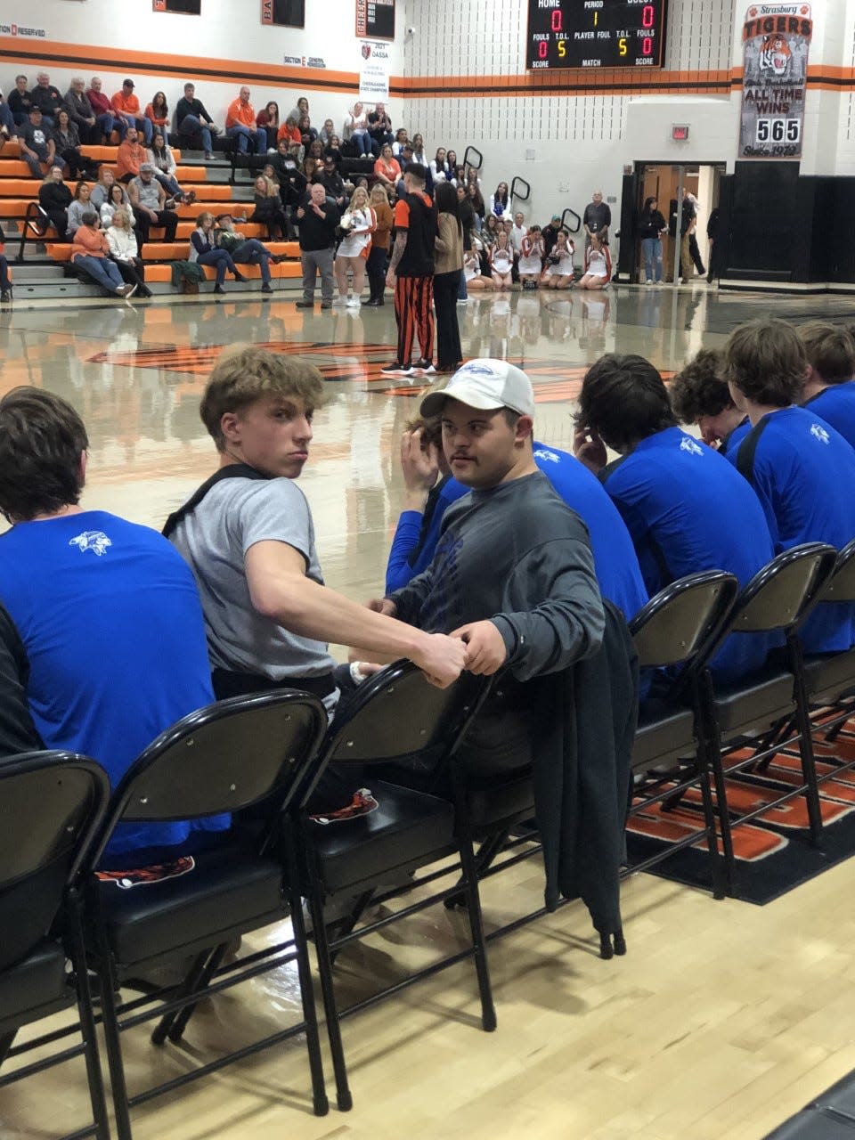 Ethan Carpenter sits beside injured Buckeye Trail player Koen Egon during a recent boys basketball game at Strasburg.