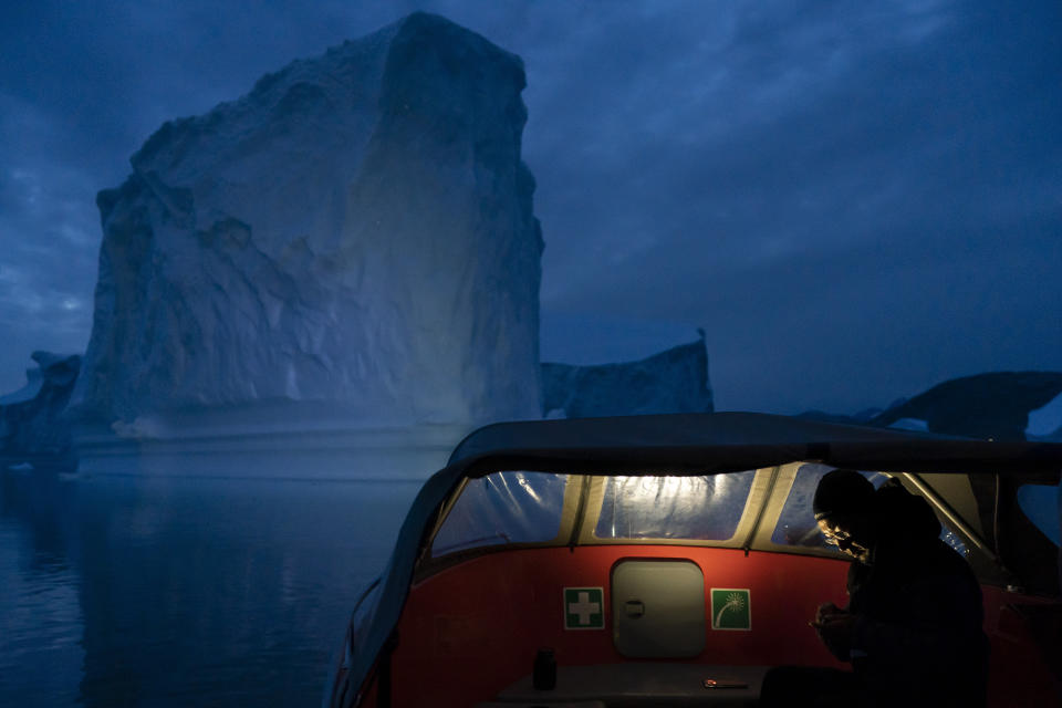 In this Aug. 15, 2019, photo, a boat navigates at night next to a large iceberg in eastern Greenland. Summer 2019 is hitting Greenland hard with record-shattering heat and extreme melt. By the end of the summer, about 440 billion tons (400 billion metric tons) of ice, maybe more, will have melted or calved off Greenland's giant ice sheet, scientists estimate. (AP Photo/Felipe Dana)