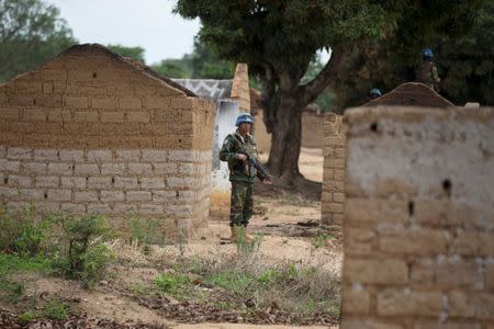 A Bangladeshi United Nations peacekeeping soldier stands among houses destroyed by violence in September, in the abandoned village of Yade, Central African Republic April 27, 2017.REUTERS/Baz Ratner -