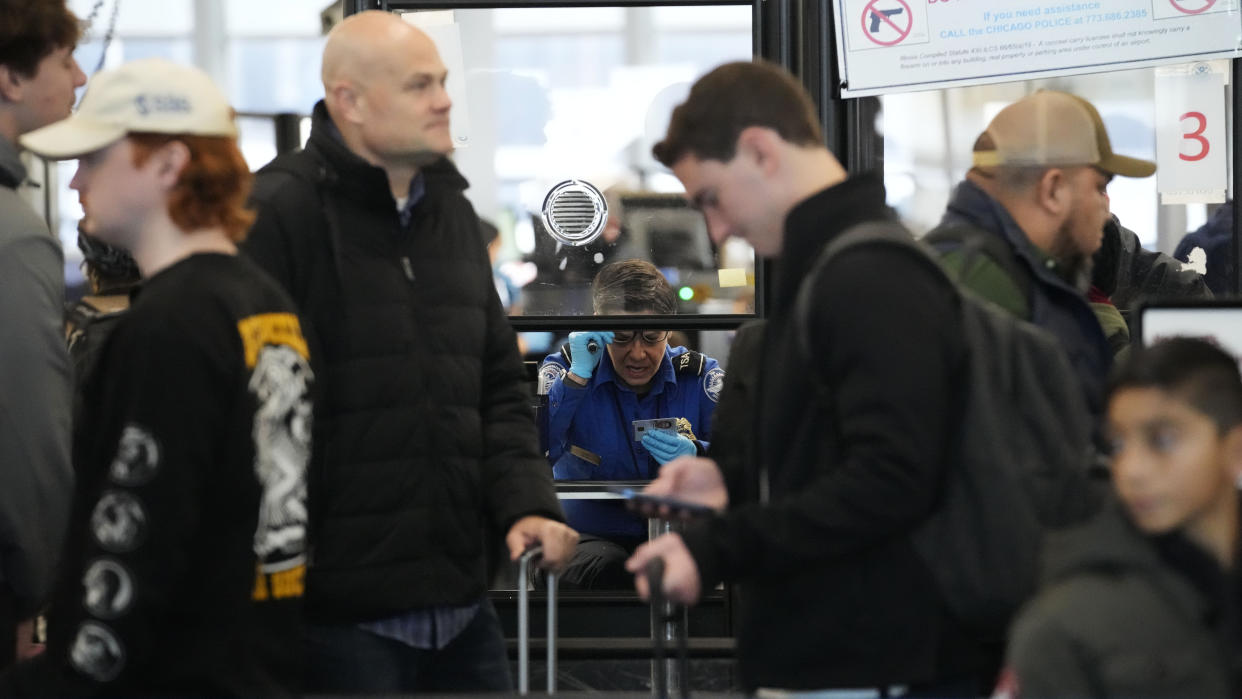 A TSA worker checks the identification of an airline passenger at O'Hare International airport in Chicago, Monday, Dec. 19, 2022. (AP Photo/Nam Y. Huh)