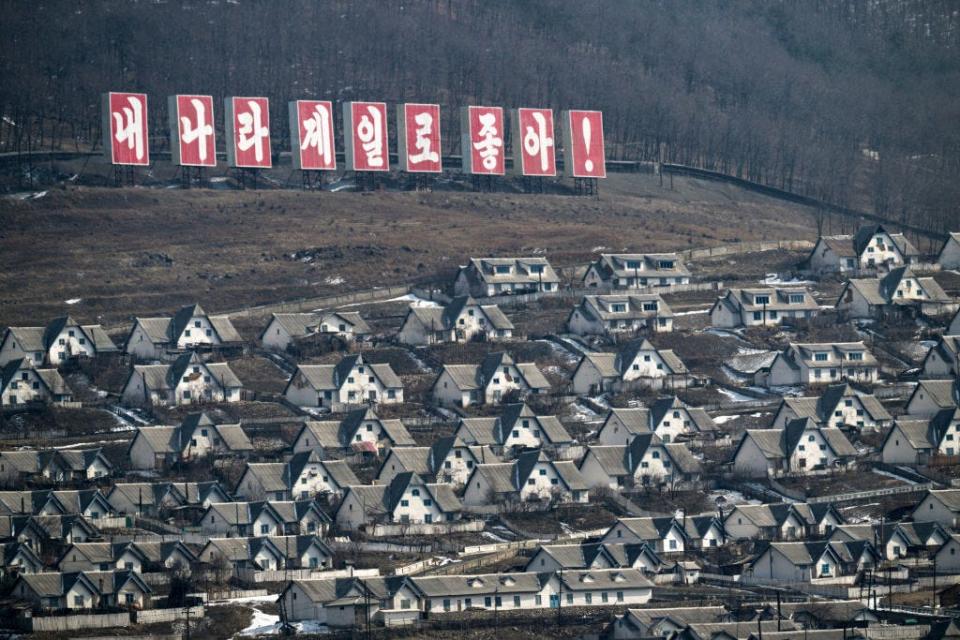 Rows of identical houses below a sign saying in Korean, "My country is the best"