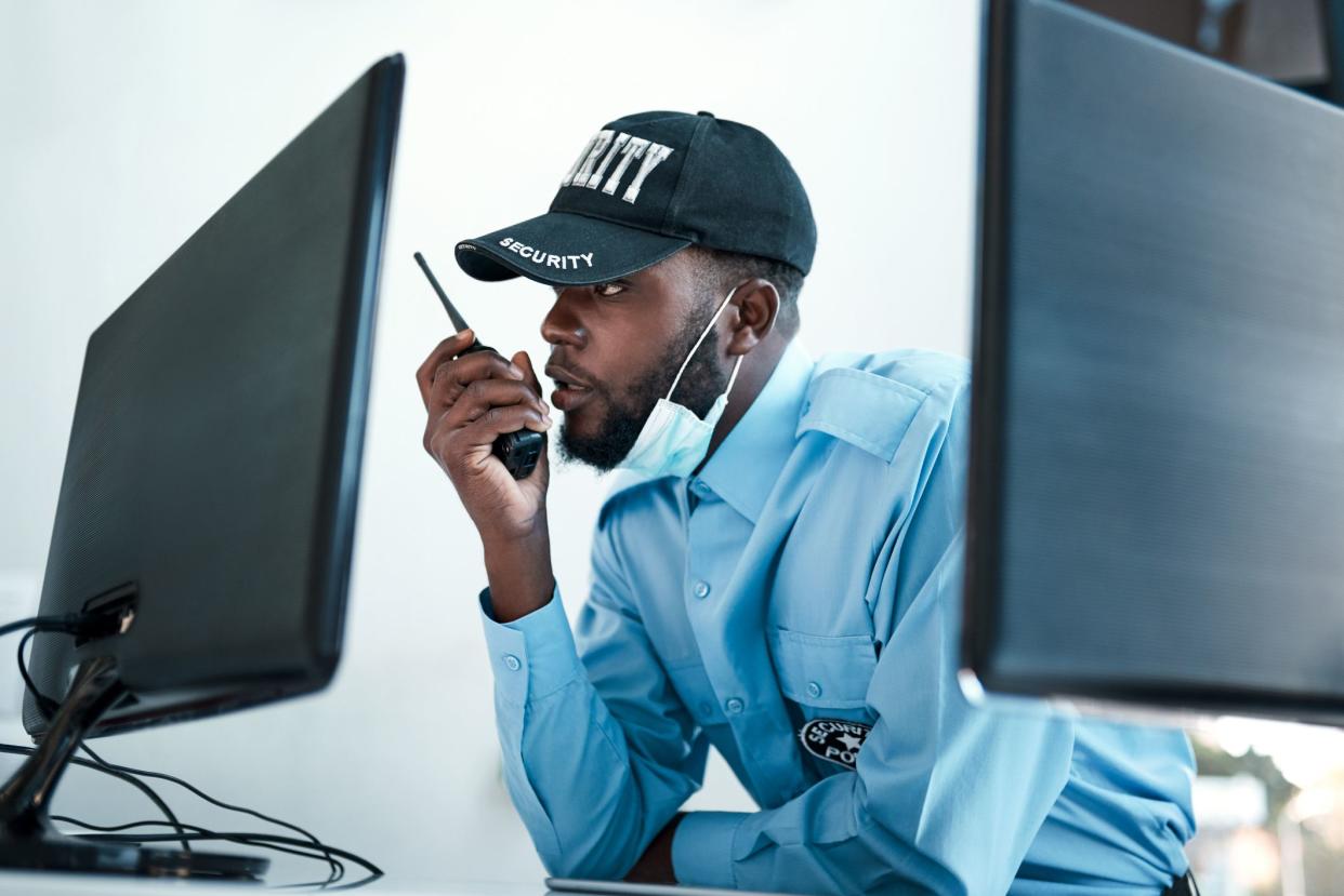 Shot of a young security guard using a two way radio while monitoring the cctv cameras