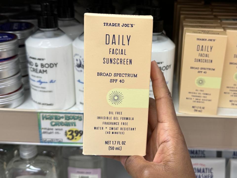 hand holding up a box of trader joe's daily facial sunscreen at a trader joes