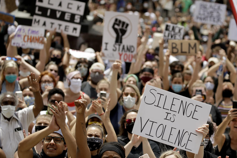 FILE - In this June 5, 2020, file photo, people hold signs as they listen to a speaker in front of city hall in downtown Kansas City, Mo., during a rally to protest the death of George Floyd. As a new generation steps up, activists and historians believe there’s important work to be done for white people: Listening to black voices and following rather than trying to lead, for one, and the deep introspection it takes to confront unconscious bias and the perks of privilege that come just from being white. (AP Photo/Charlie Riedel, File)