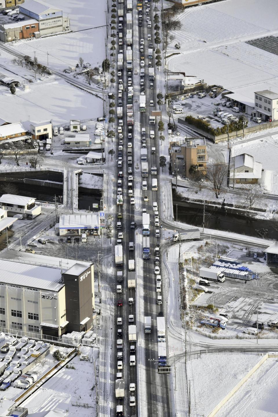 Vehicles are stranded due to heavy snow at Japan National Route 1 in Kyoto, western Japan Wednesday, Jan. 25, 2023. Snow and cold weather were affecting much of Japan on Wednesday, disrupting highway, air and train travel, and more snow and cold temperatures were forecast. (Kyodo News via AP)