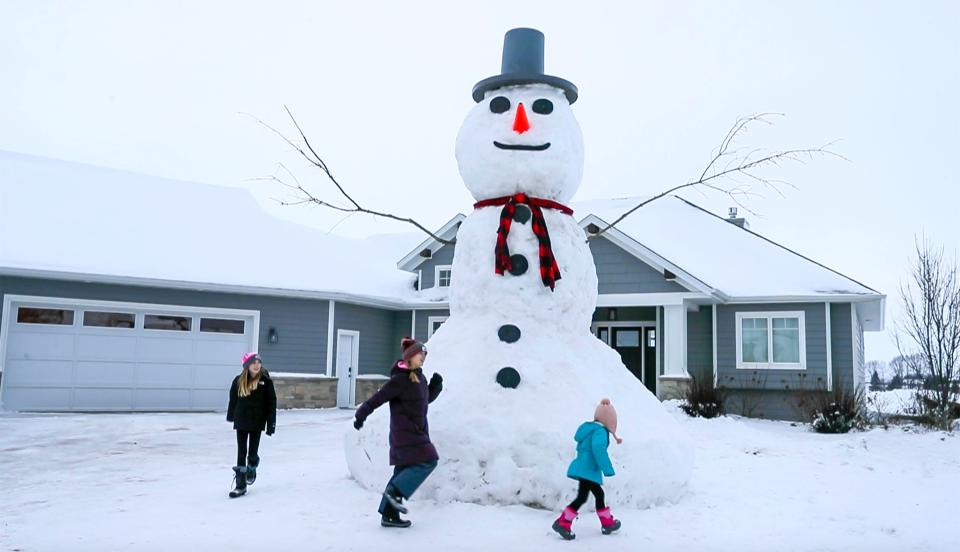 Children march round the 18-foot-tall snowman, Monday, January 22, 2024, that Jon Voskuil and several of his friends created in his front yard over the weekend in Cedar Grove, Wis.