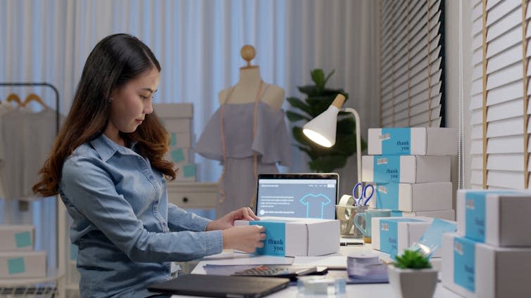 Woman packing parcels at desk.