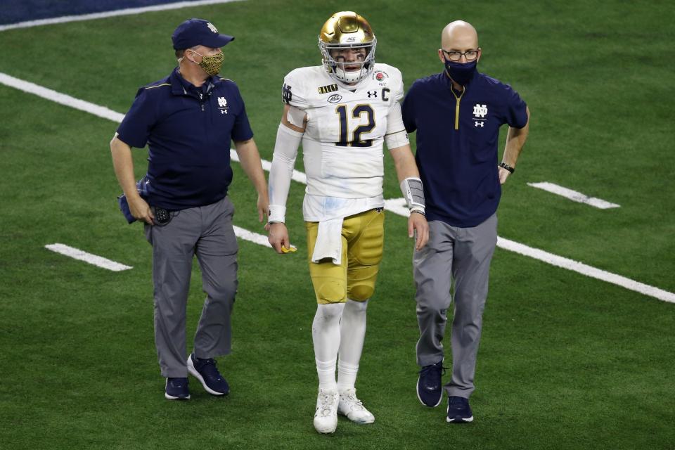 Notre Dame quarterback Ian Book is helped off the field by team medical personnel in the second half of the Rose Bowl NCAA college football game against Alabama in Arlington, Texas, Friday, Jan. 1, 2021. (AP Photo/Roger Steinman)