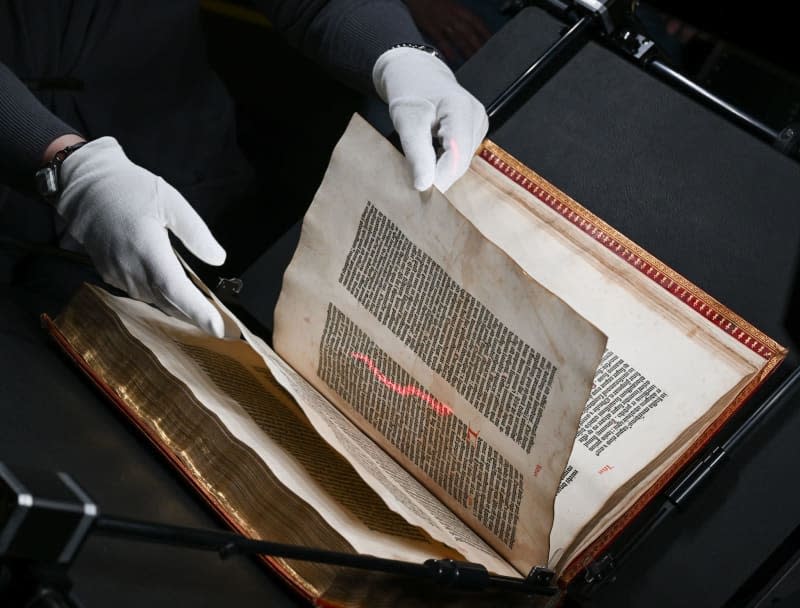 Conservator at the Gutenberg Museum Dorothea Mueller turns the pages of the Shuckburgh copy of the Gutenberg Bible, which is being digitized in a special device from the company "Microbox" in Bad Nauheim. Arne Dedert/dpa