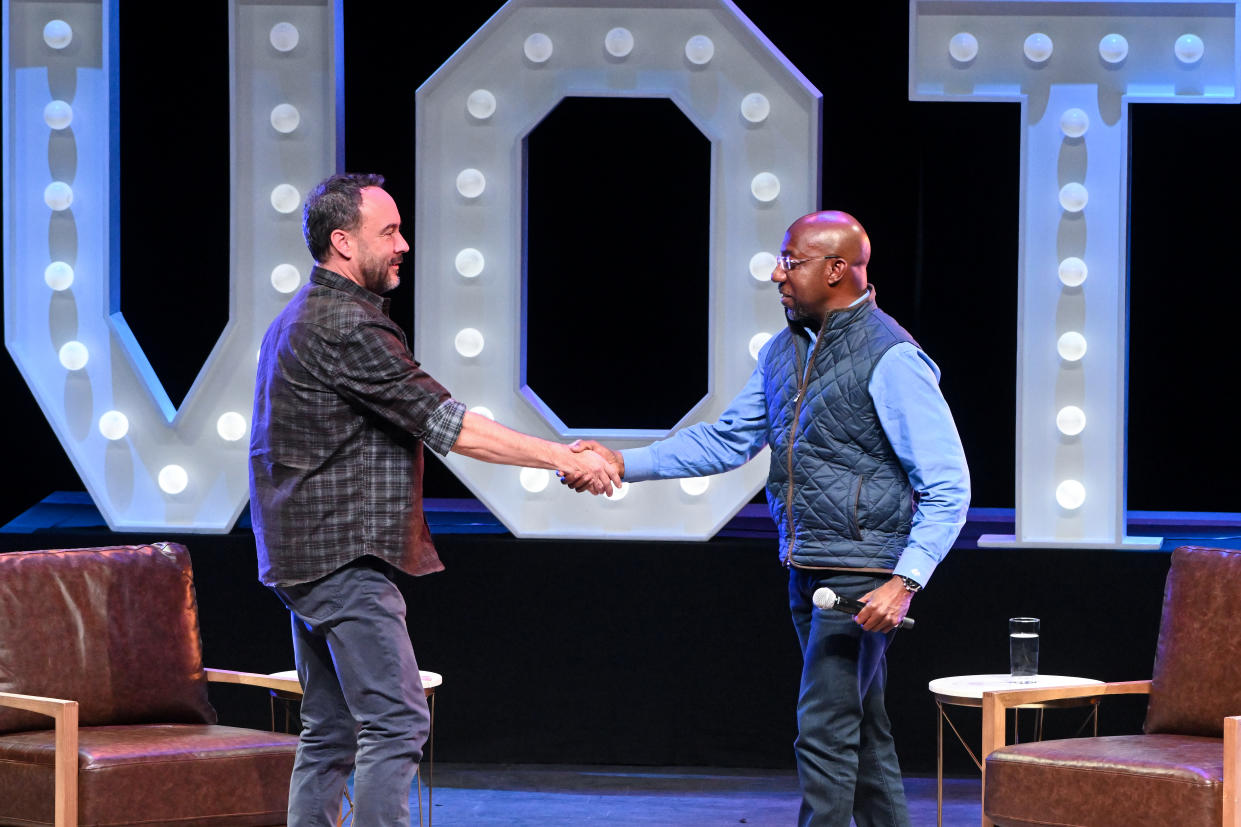 Musician Dave Matthews and Sen. Raphael Warnock shake hands onstage.