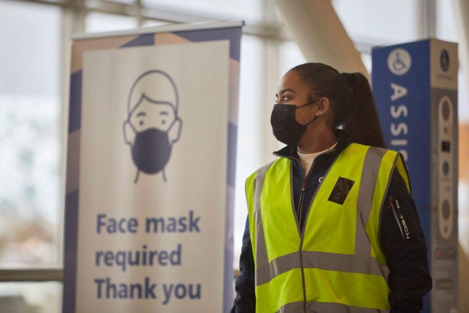 A security worker stands by sign reminding travelers to wear face masks at Amsterdam Schiphol airport on December 2, 2021 in the Netherlands.