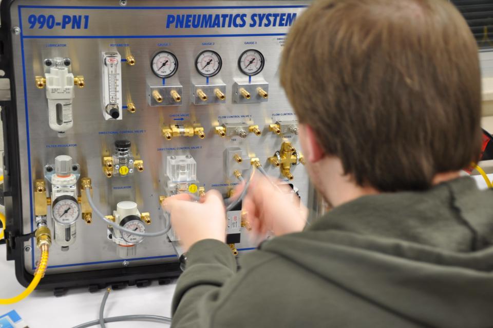 James Hill, 18, a senior at West Branch High School, creates motion with air using this pneumatics system on Thursday, Jan. 11, 2024, during the school's first Industrial Maintenance Showcase.