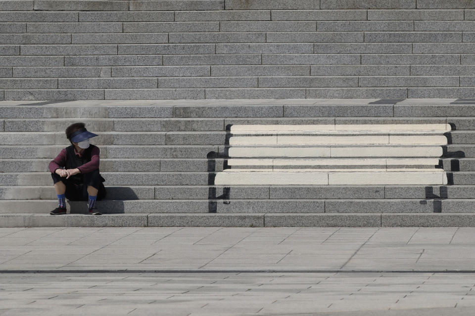 A woman wearing a face mask takes a look at stairs on which a bench is painted in Goyang, South Korea, Friday, April 9, 2021. (AP Photo/Lee Jin-man)