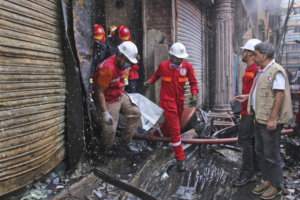 Firefighters retrieve a body from the site of a fire that broke out late Wednesday in closely set buildings in Dhaka, Bangladesh, Thursday, Feb. 21, 2019. A devastating fire raced through at least five buildings in an old part of Bangladesh's capital and killed scores of people. (AP Photo/Rehman Asad)