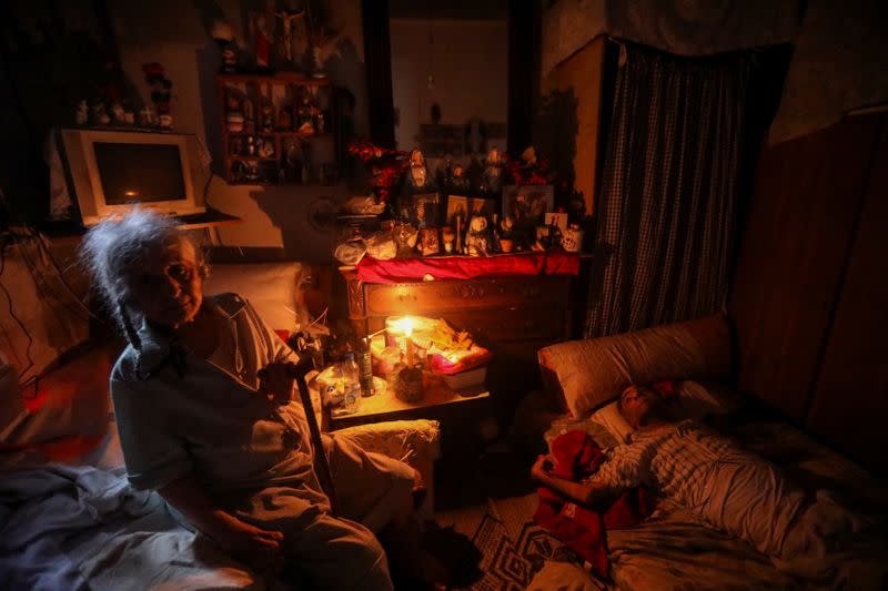 A woman uses a candle to light up the room due to a power cut in Beirut