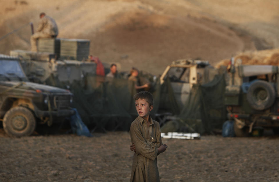 FILE - In this Monday, Sept. 14, 2009 file photo made by Associated Press photographer Anja Niedringhaus,an Afghan boy looks on as German ISAF soldiers prepare a temporary camp to overnight during a long term patrol in the mountainous region of Feyzabad, east of Kunduz, Afghanistan. Niedringhaus, 48, an internationally acclaimed German photographer, was killed and an AP reporter was wounded on Friday, April 4, 2014 when an Afghan policeman opened fire while they were sitting in their car in eastern Afghanistan. (AP Photo/Anja Niedringhaus, File)