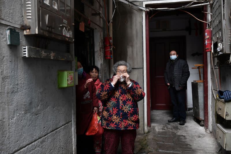 Residents wearing face masks are seen outside their houses at a residential area in Wuhan