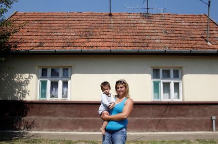 Nikoletta Futo holds one of her triplet sons in the street outside their home in Kanjiza, Serbia, July 7, 2017, after a grant from the Hungarian government enabled the family of six to purchase a house on the outskirts of the town. REUTERS/Bernadett Szabo
