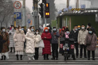 Pedestrians wearing face masks to help protect from the coronavirus wait to cross an intersection in the Central Business District of Beijing, Monday, Jan. 24, 2022. A fresh outbreak in Beijing has prompted authorities to test millions and impose new measures two weeks ahead of the opening of the Winter Olympics, even as Chinese officials on Monday lifted a monthlong lockdown on the northern city of Xi'an and its 13 million residents. (AP Photo/Andy Wong)