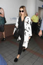 <p>Alba strut through LAX in an all-black ensemble, accessorizing with a white floral duster and studded slides.</p>