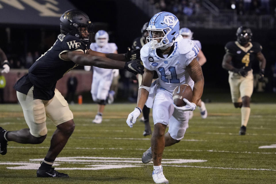 North Carolina wide receiver Josh Downs (11) tries to run past Wake Forest defensive back Isaiah Wingfield (8) during the second half of an NCAA college football game in Winston-Salem, N.C., Saturday, Nov. 12, 2022. (AP Photo/Chuck Burton)