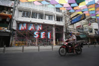 A motorcyclist wearing a face mask to help curb the spread of the coronavirus moves past Khao San road, a popular hangout for Thais and tourists in Bangkok, Thailand, Monday, April 26, 2021. Cinemas, parks and gyms were among venues closed in Bangkok as Thailand sees its worst surge of the pandemic. A shortage of hospital beds, along with a failure to secure adequate coronavirus vaccine supplies, have pushed the government into imposing the new restrictions. (AP Photo/Anuthep Cheysakron)