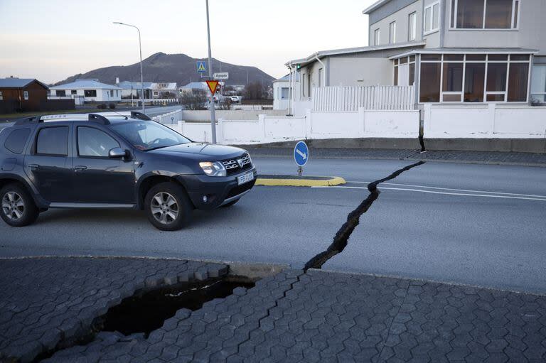 Un automóvil avanza hacia una fisura en una carretera en la ciudad de Grindavik, Islandia, el lunes 13 de noviembre de 2023, luego de una actividad sísmica 