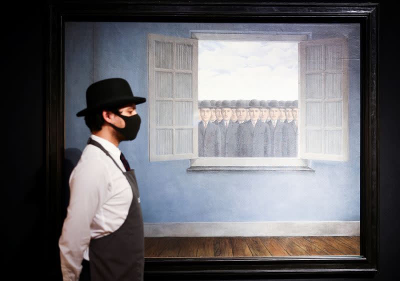 Un asistente de la galería posa junto a una obra de arte titulada 'Le Mois des Vendanges' del pintor René Magritte en la casa de subastas Christie's, en Londres, Gran Bretaña.