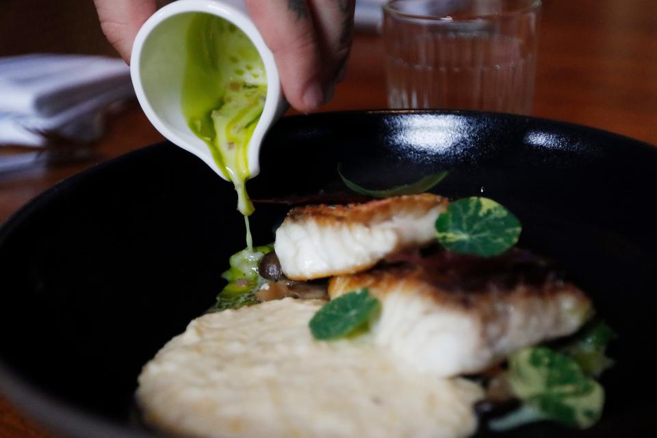 Executive Chef of the Drayton Hotel Benjamin Murray pours a sauce on the Snapper and Grits at the St. Neo's Brasserie in the Drayton Hotel in Savannah, GA Saturday, May 28, 2022.