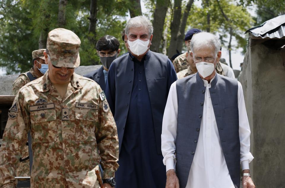 Pakistan's Foreign Minister Shah Mahmood Qureshi, center, Defense Minister Pervez Khattak, right, walk with a senior army officer during their visit to forward area post along a highly militarized frontier in the disputed region of Kashmir, in Chiri Kot sector, Pakistan, Monday, Aug. 3, 2020. The region's top Pakistani military commander briefed ministers about Indian cease-fire violations in Kashmir, which is split between Pakistan and India and claimed by both in its entirety. (AP Photo/Anjum Naveed)