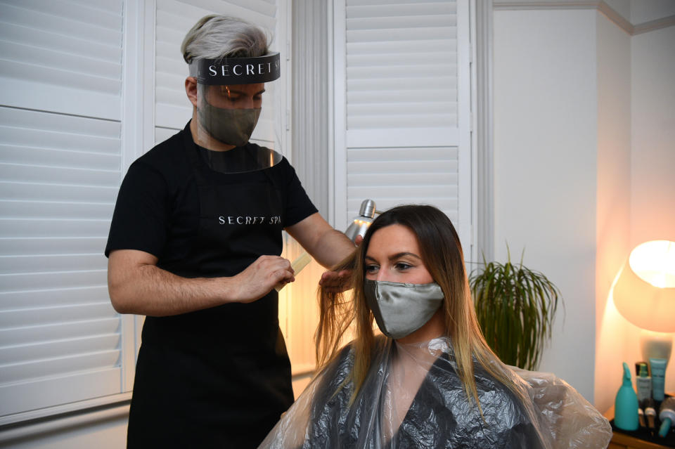 Secret Spa hair stylist Nas Ganev cuts the hair of Amy Pallister, 27, just after midnight at her home in Balham, south London. Five housemates desperate for a trim and tan booked Secret Spa stylist Nas Ganev and tan artist Magdelaine Gibson to visit their home at one minute past midnight for haircuts and bronzed skin as coronavirus restrictions eased across England. Secret Spa, which offers at-home beauty and wellness services in London, Manchester and Brighton, have extended their opening hours to accommodate 350 beauty treatments on the first day of restrictions lifting, with the first appointments beginning at one minute past midnight. Picture date: Monday April 12, 2021.