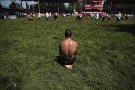 A wrestler, doused in olive oil, watches as others compete on the third and last day of the 660th instalment of the annual Historic Kirkpinar Oil Wrestling championship, in Edirne, northwestern Turkey, Sunday, July 11, 2021.Thousands of Turkish wrestling fans flocked to the country's Greek border province to watch the championship of the sport that dates to the 14th century, after last year's contest was cancelled due to the coronavirus pandemic. The festival, one of the world's oldest wrestling events, was listed as an intangible cultural heritage event by UNESCO in 2010. (AP Photo/Emrah Gurel)