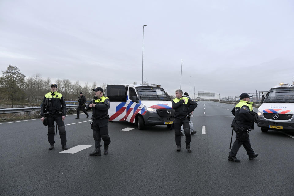 Police officers stop traffic on the main highway around Amsterdam as climate activists block it near the former headquarters of a ING bank to protest its financing of fossil fuels, Saturday, Dec. 30, 2023. Protestors walked onto the road at midday, snarling traffic around the Dutch capital in the latest road blockade organized by the Dutch branch of Extinction Rebellion. (AP Photo/Patrick Post)