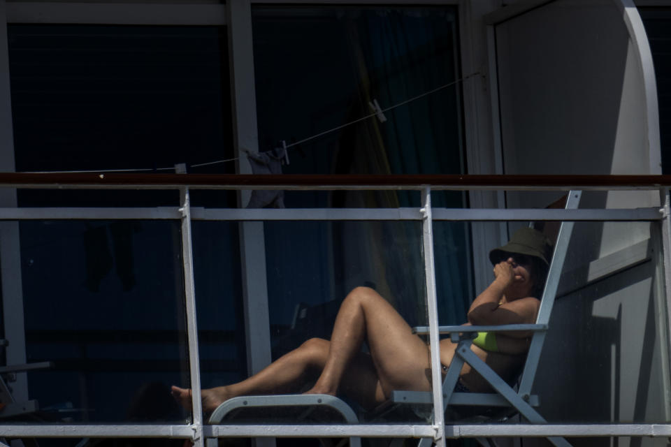A passenger is photographed on the cruise ship MSC Armony, moored in the port of Barcelona, Spain, Wednesday, April 3, 2024. Authorities said Wednesday that a group of 69 Bolivians are not being allowed to disembark from a cruise ship in the Spanish northeastern port of Barcelona because they lack valid documents to enter the European Union's Schengen area. (AP Photo/Emilio Morenatti)