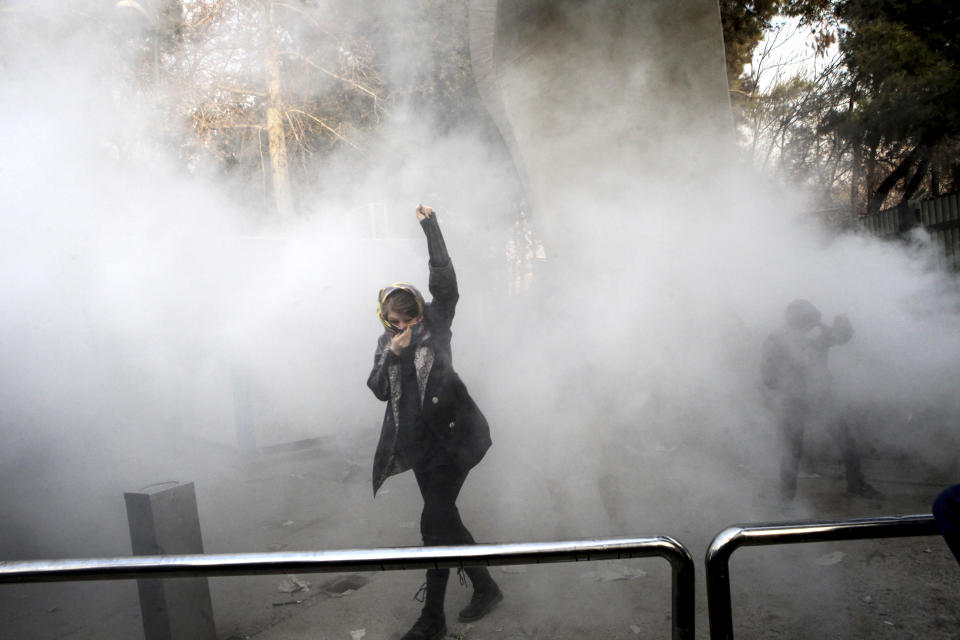 FILE-- In this Dec. 30, 2017 file photo, taken by an individual not employed by the Associated Press and obtained by the AP outside Iran, a university student attends a protest inside Tehran University while a smoke grenade is thrown by anti-riot Iranian police, in Tehran, Iran. Ahead of the 40th anniversary of Iran’s Islamic Revolution, the country’s government is allowing more criticism to bubble up to the surface. Analysts say that may serve as a relief valve in this nation of 80 million people, which already has seen widespread, leaderless protests rock the country at the start of the year. (AP Photo, File)