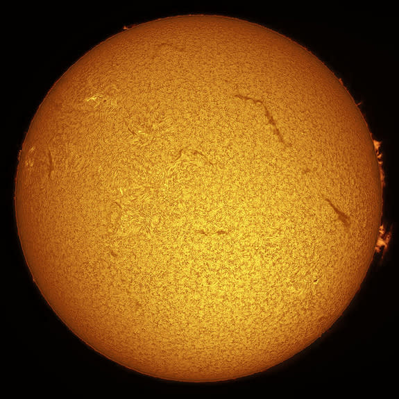 This is a typical view of the sun as seen through an H-alpha telescope. Details in the sun’s chromosphere that are visible include fine, carpet-like spicules and long, dark filaments across the disk as well as delicate prominences along the edg