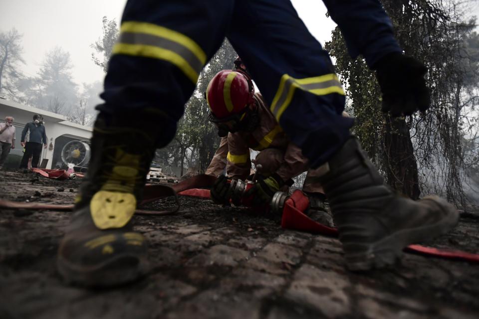 Firefighters operate in Asmini village on Evia island, about 193 kilometers (120 miles) north of Athens, Greece, Sunday, Aug. 8, 2021. Pillars of billowing smoke and ash turned the sky orange and blocked out the sun above Greece's second-largest island Sunday as a days-old wildfire devoured pristine forests and encroached on villages, triggering more evacuation alerts. (AP Photo/Michael Varaklas)