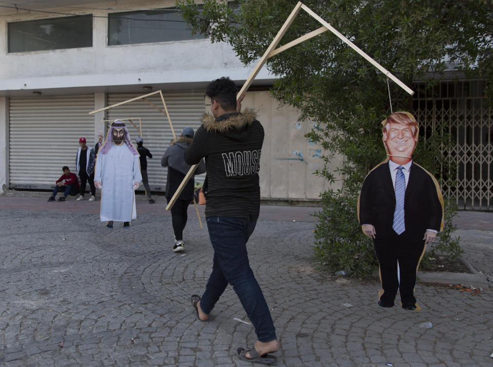 Activists carry cardboard cutouts that depicts US President Donald Trump that is hung to a gallows, during a rally for the Shiite group Asaib Ahl al-Haq, in Baghdad, Iraq, Saturday, Dec. 14, 2019. (AP Photo/Nasser Nasser)