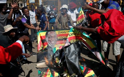 MDC supporters burn an election banner with the face of Zimbabwe's President Emmerson Mnangagwa - Credit: Reuters