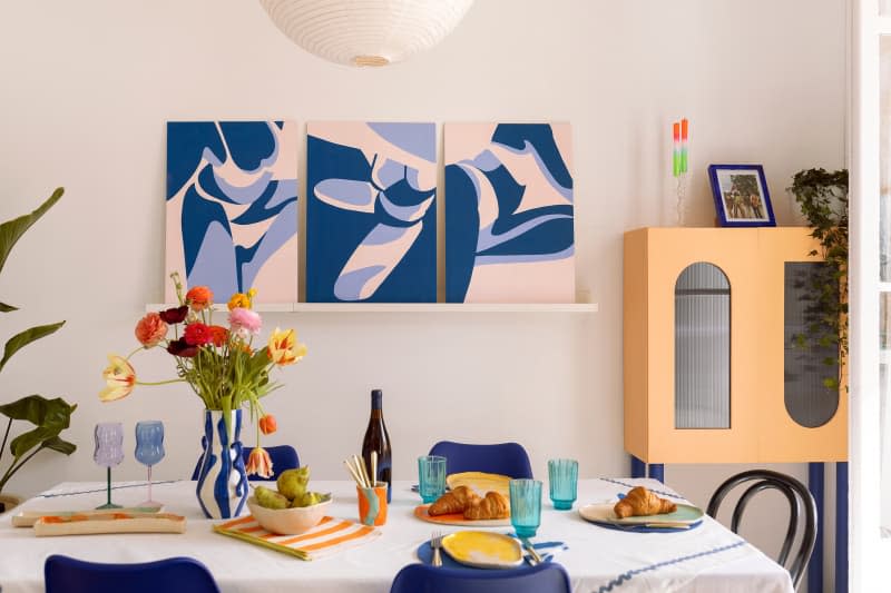 Colorful glassware and plants sit on a dining room table.