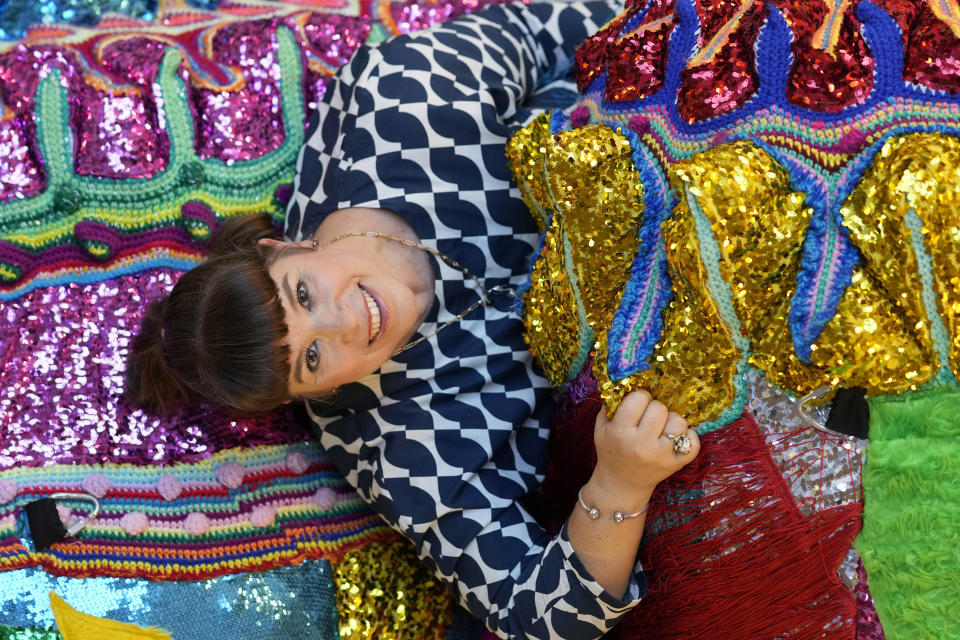 Portuguese artist Joana Vasconcelos poses for a picture amid one of her works on the floor of at her studio in Lisbon, Friday, Nov. 11, 2022. Vasconcelos has built her reputation over the past two decades. Her trademark features are large, flamboyant pieces that juxtapose the high brow and low brow, draw on Portuguese handicraft traditions, allude to women's rights, and possess a stealthy sense of humor. (AP Photo/Armando Franca)