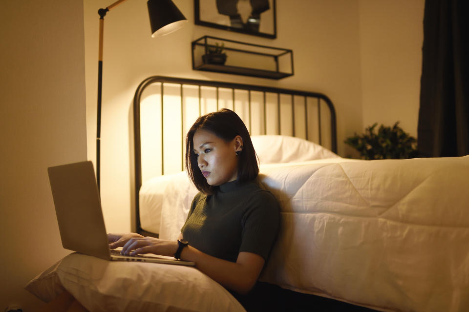 Woman staying up late in bedroom on laptop. (Getty Images)