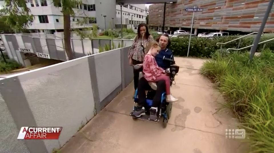 Damion Miller is pictured in a wheelchair with daughter Madison, 5, and partner Celeste.