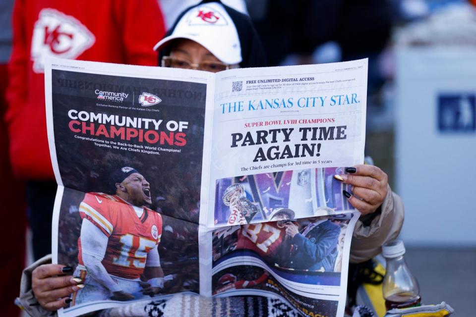A fan reads a local newspaper during the parade.<span class="copyright">David Eulitt—Getty Images</span>