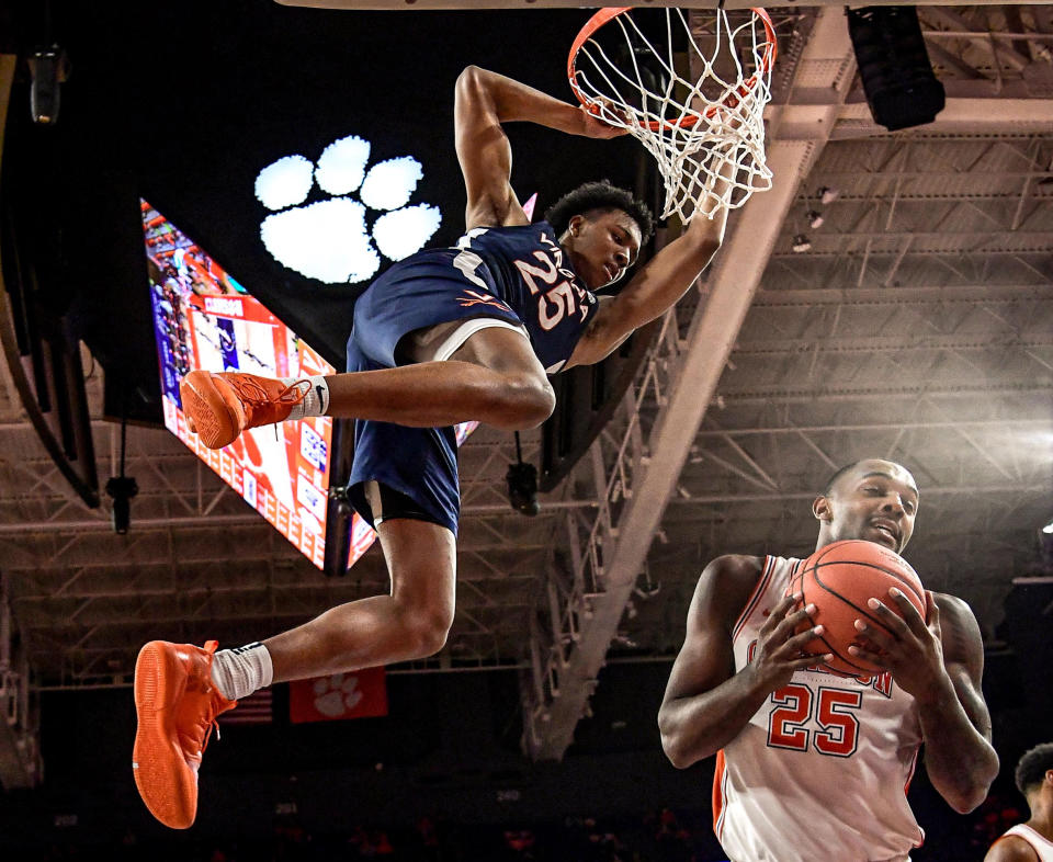 Jan 16, 2021; Clemson, South Carolina, USA; Virginia Cavaliers guard Trey Murphy III (25) hangs on the rim after dunking against Clemson Tigers forward Aamir Simms (right) during the second half at Littlejohn Coliseum. 