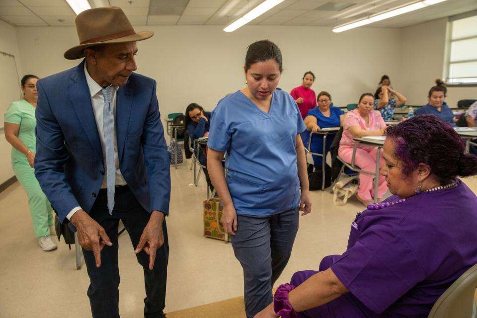 One woman is learning to lift another woman out of a chair.