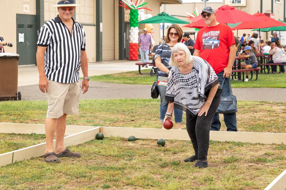 Valerie Halloran gets a quick lesson on how to play Bocce Ball as Mike Halloran and Denise Jones who play in a Bocce Ball league watch on at Festa Italiana at Lodi Grape Festival on June  12th. Dianne Rose/For The Record