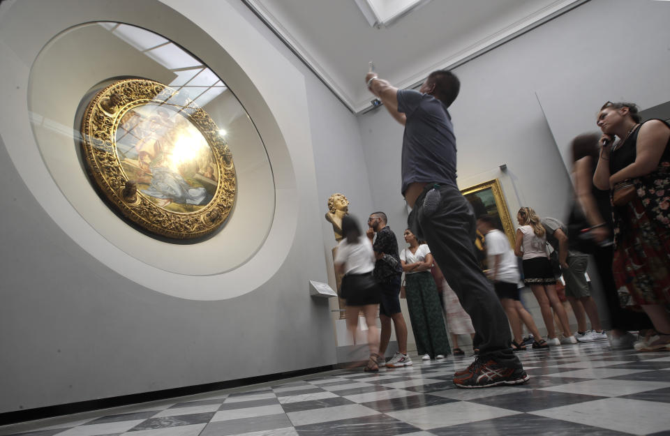 Visitors admire Renaissance painter Michelangelo Buonarroti's painting "Holy Family, with the young St. John the Baptist", also known as the “Doni Tondo”, at the Uffizi Gallery museum, in Florence, Italy, Tuesday, Aug. 6, 2019. With the paintings safely behind nearly invisible barriers, no annoying ropes need separate visitors from the paintings, and, to Uffizi Gallery director Eike Schmidt’s delight, museum-goers press their noses right up against the climate-controlled display cases. AP Photo/Luca Bruno)